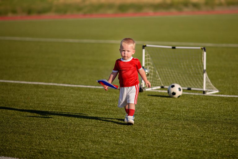 happy-babyy-little-boy-playing-soccer-with-ball-field-near-gate (1)