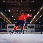 rear-view-hockey-player-skating-towards-opposite-team-trying-score-hall-interior